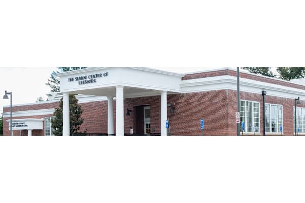 The front of a building with a white roof and pillars.